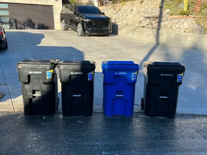 Four clean trash carts lined up at the curb